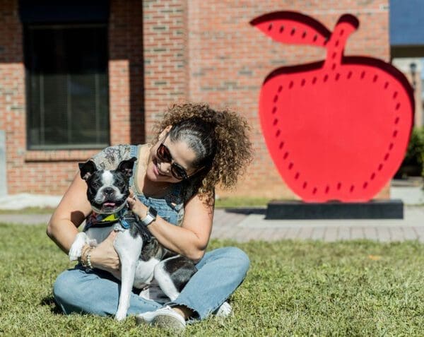 a woman and her dog sitting in the grass
