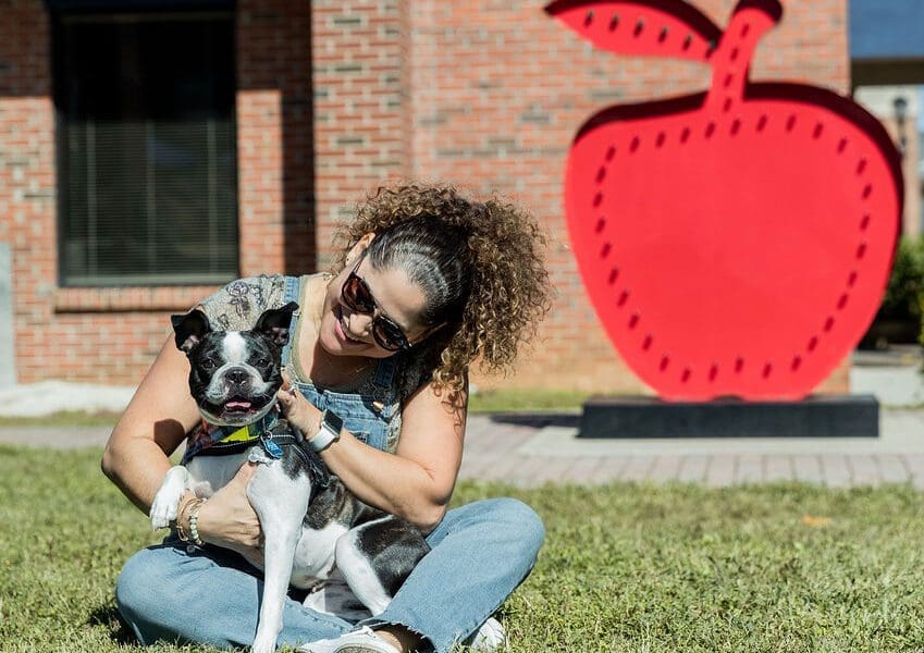 a woman and her dog sitting in the grass